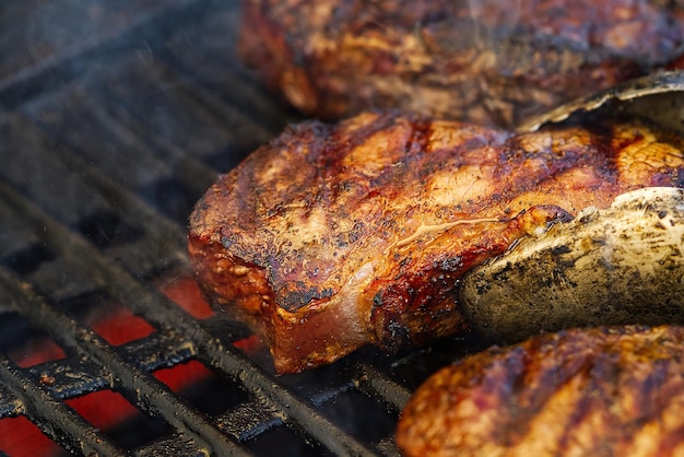 Grillen von Steaks auf flammendem Gasgrill und Schuss mit selektivem Fokus Hinterhofgrillen von saftigem Steak ri