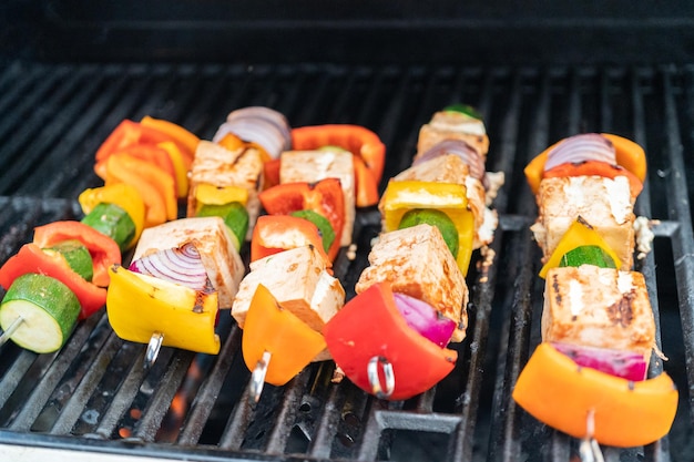 Foto grillender vegetarischer tofu-kebab mit in scharfer sauce mariniertem gemüse.