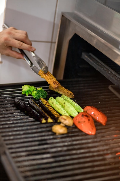 Grillgemüse tomaten mais auberginen zucchini pilze paprika werden in einer professionellen grillmaschine zubereitet chef grillt gemüse in der restaurantküche