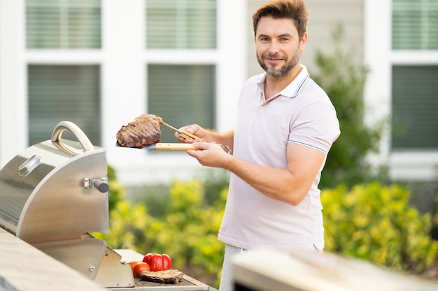 Grillmeister mittleren Alters hispanischer Mann in Schürze zum Grillen und Grillen von Lebensmitteln Mann halten c