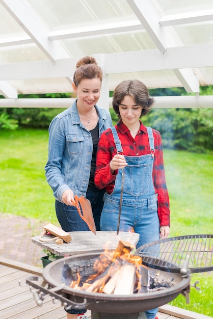 Grillparty im Garten mit Mutter und ihrer Tochter am Grill in einem Land