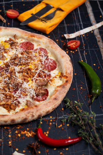 Grillpizza mit Schweinefleisch, Käse, Pfeffer und Soße, Nahaufnahme auf dem horizontalen Tisch