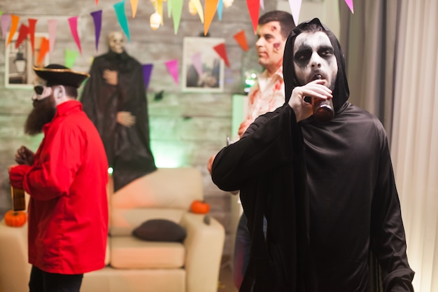 Grim reaper desfrutando de sua cerveja na celebração do halloween. Homem assustador.