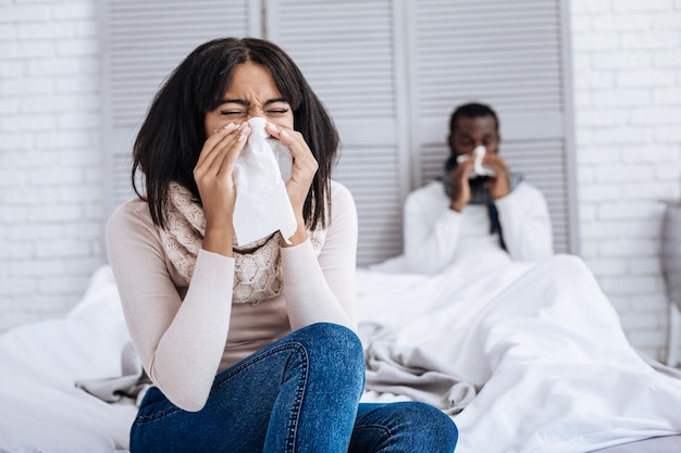 Gripe sem fim. jovem casal cansado e doente com espirros, curando desesperadamente sua terrível gripe