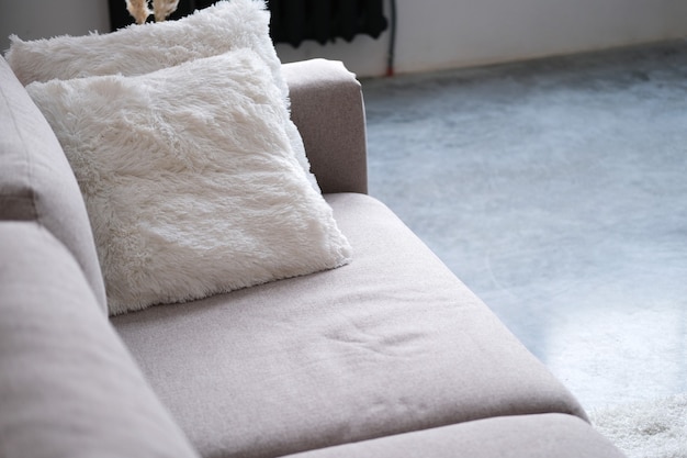 Gris brillante con sofá de almohada blanca en primer plano de la sala de estar. De cerca
