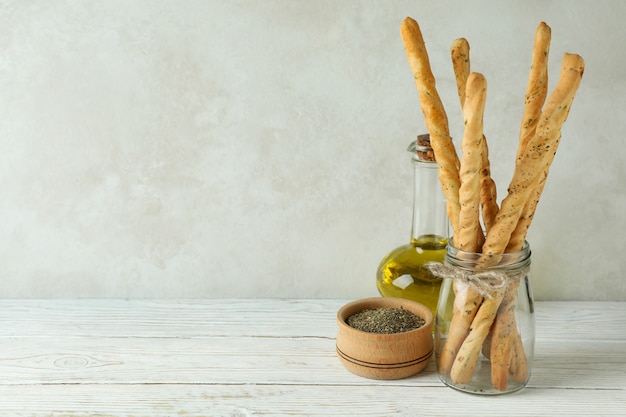 Grissini, aceite y especias en mesa de madera blanca