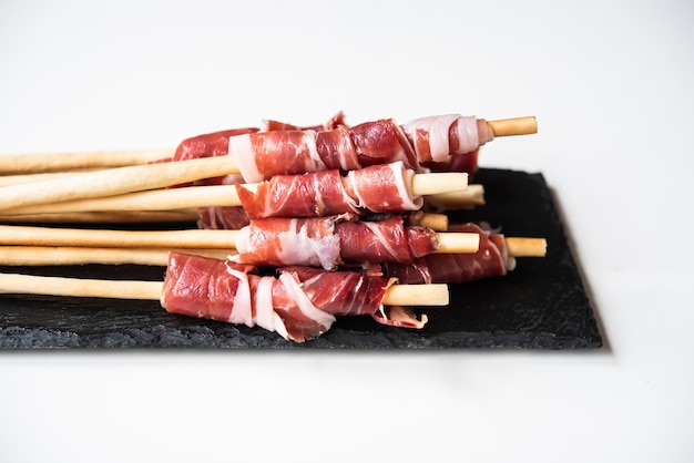 Grissini con jamón ibérico de bellota sobre fondo blanco Tapa española para eventos o celebraciones