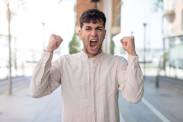 gritando agressivamente com uma expressão de raiva ou com os punhos cerrados comemorando o sucesso