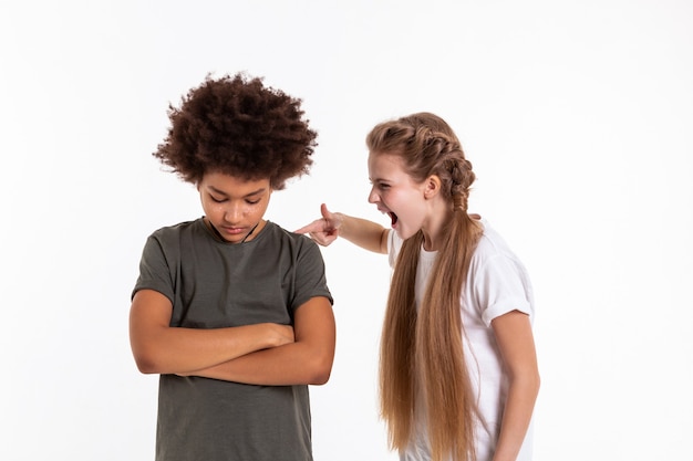 Gritando agressivamente. Menina louca e expressiva tocando seu amigo moreno e murcho e gritando com ele