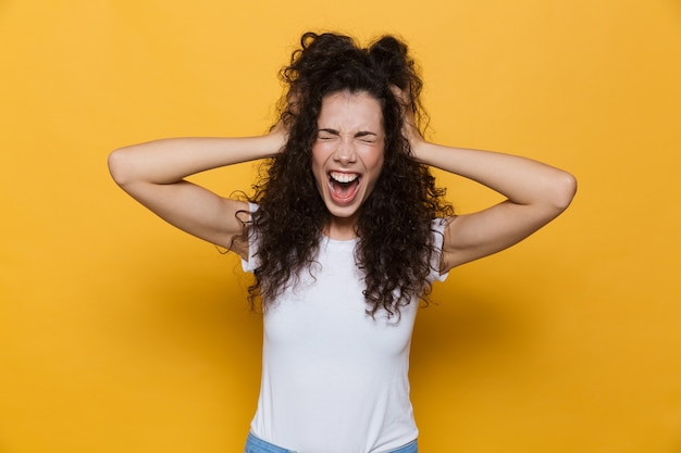 Gritando emocionada joven linda mujer posando aislada en amarillo.