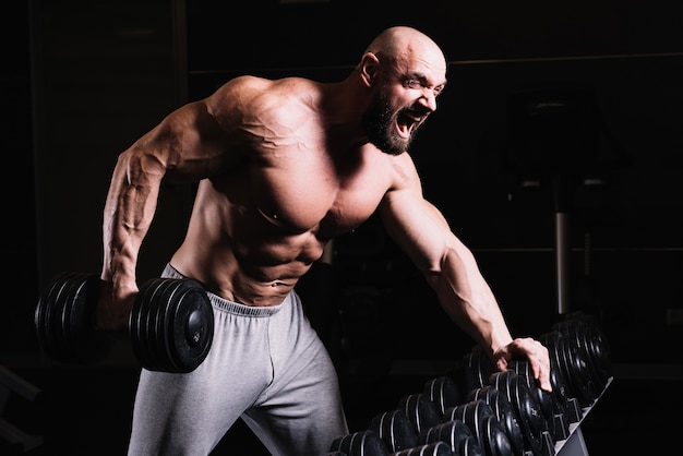 Foto gritando homem calvo com dumbbell