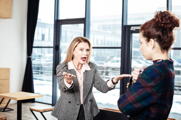 Foto gritando a la secretaria. empresaria emocional con labios rojos gritando a su nueva secretaria perezosa