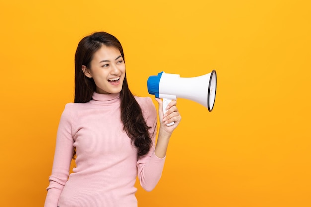 Grite em voz alta com megafone Jovem mulher asiática bonita anuncia com voz sobre promoções e anúncios de produtos a um preço com desconto Conceito de compras e moda