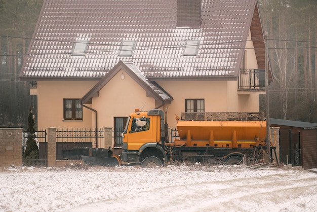 Gritter trabalhando na rua suburbana após uma forte nevasca Limpeza de neve nas estradas Espalhamento de sal