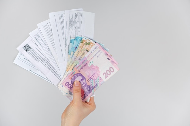 Griwna-Banknoten und Zahlungen für Versorgungsunternehmen liegen in den Händen einer Person, die in der Ukraine Gas, Strom und Wasser bezahlt