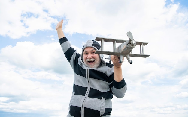 Grizzle senior jubilado hombre maduro en jubilación anciano sobre fondo de cielo con avión de juguete