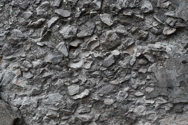 Grobe dunkelgraue Steinmauer aus Kopfsteinpflaster und Beton Textur unebener Steinhintergrund