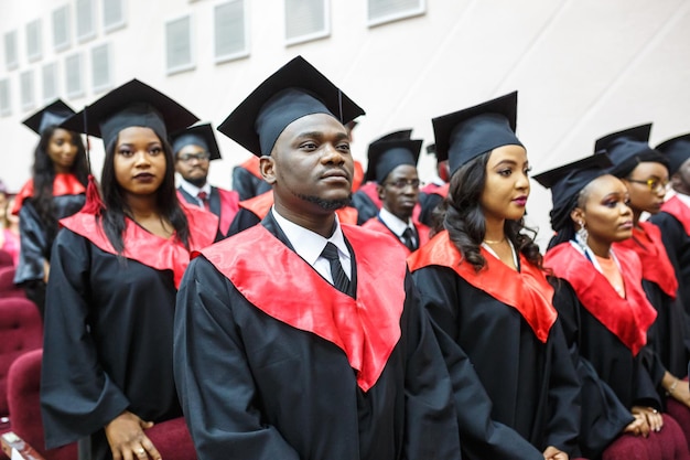 GRODNO BELARUS JUNI 2018 Ausländische afrikanische Medizinstudenten in quadratischen akademischen Abschlusskappen und schwarzen Regenmänteln während des Beginns mit Diplomen