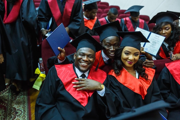 GRODNO BELARUS JUNI 2018 Ausländische afrikanische Medizinstudenten in quadratischen akademischen Abschlusskappen und schwarzen Regenmänteln während des Beginns mit Diplomen