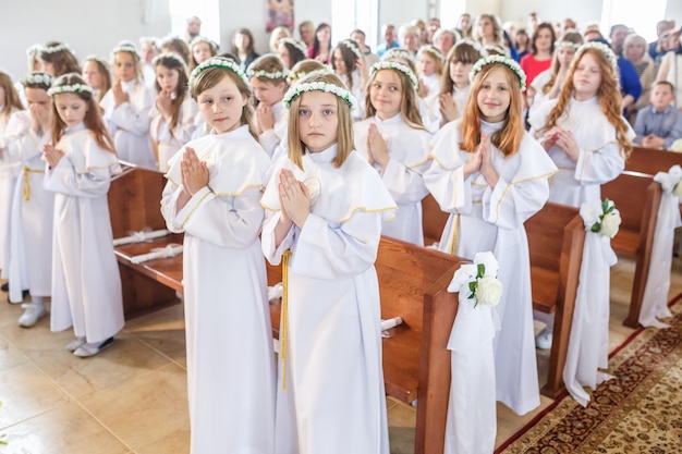 GRODNO BIELORRÚSSIA MAIO DE 2019 Crianças na Igreja Católica estão esperando a primeira comunhão eucaristia Anjinhos em roupas brancas