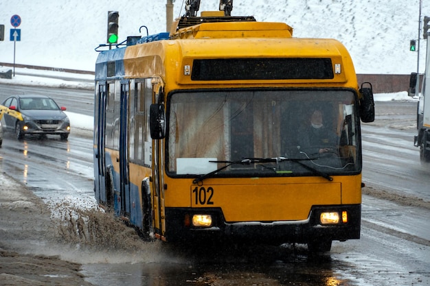 Grodno Bielorrusia 9 de febrero de 2022 Coches que pasan en un gran charco durante la lluvia y el aguanieve Grandes salpicaduras debajo de las ruedas del coche Barro, nieve y charcos en una carretera principal de la ciudad