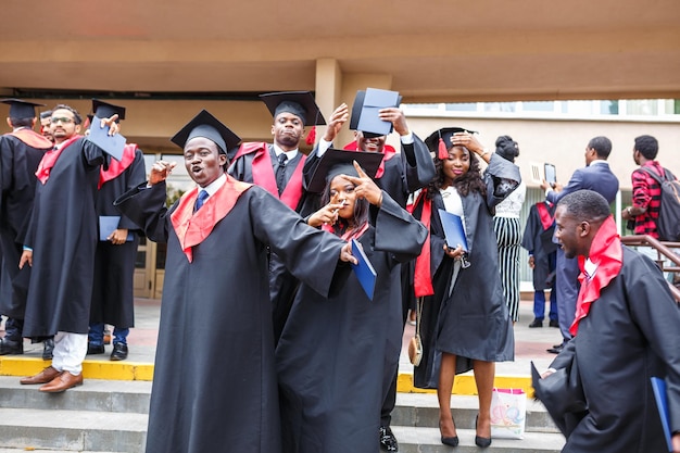 GRODNO BIELORRUSIA JUNIO DE 2018 Felices estudiantes de medicina africanos extranjeros con gorras de graduación académicas cuadradas e impermeables negros durante el comienzo de los diplomas después de terminar los estudios