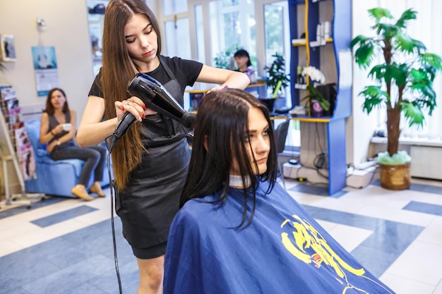 GRODNO BIELORRUSIA MAYO 2016 maestro peluquero coiffeur haciendo un peinado en peluquería para mujer joven