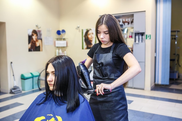 GRODNO WEISSRUSSLAND MAI 2016 Meisterfriseur Coiffeur, der eine Frisur im Friseursalon für junge Frau tut