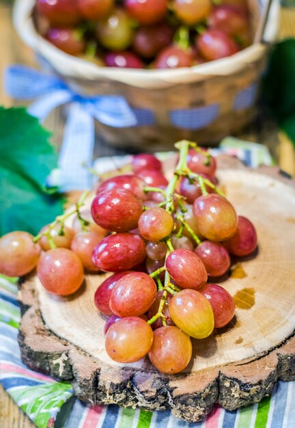 Grono de uvas rosadas sobre un soporte de madera