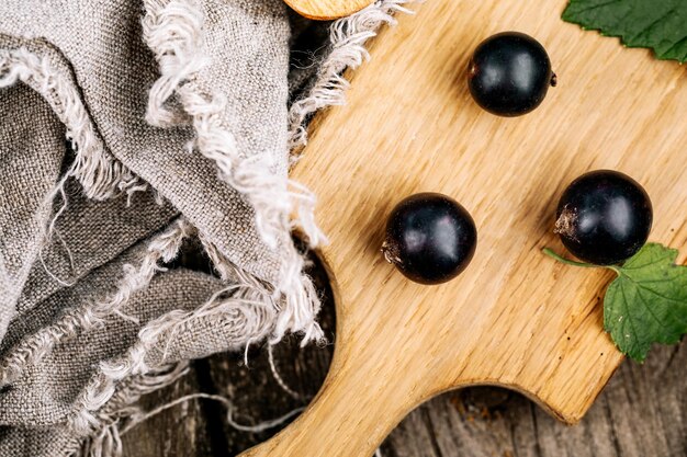 Groselha preta fresca um punhado de frutas em uma mesa de madeira