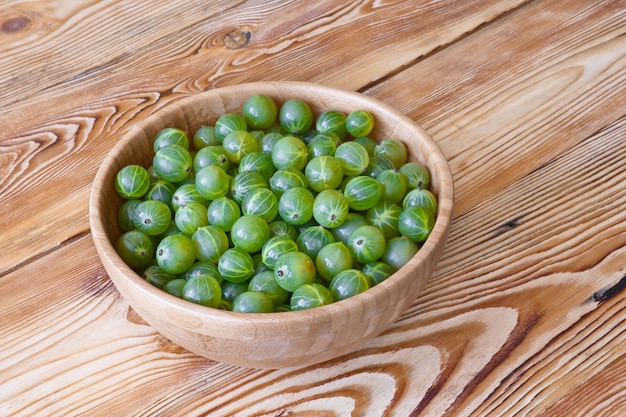 Groselhas verdes maduras em tigela na mesa de madeira