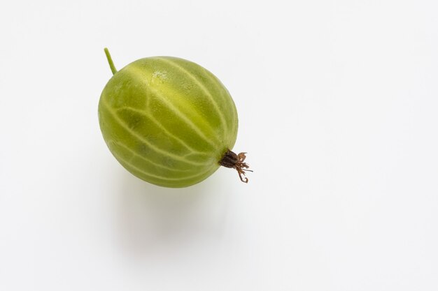 Grosella espinosa verde húmeda jugosa. Aislado en un fondo blanco. Copie el espacio.