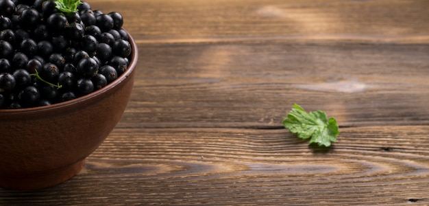 Grosella negra en mesa de madera con ramillete de hojas