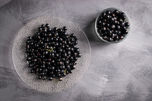 Foto grosella negra sobre mesa gris con ramillete de hojas