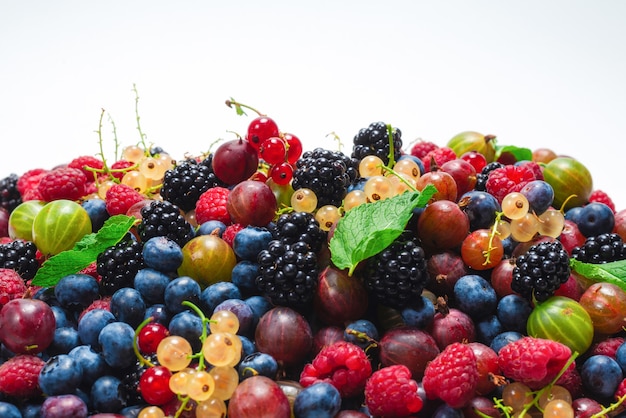 Grosellas, arándanos, moras, frambuesas, grosellas blancas y rojas aisladas sobre superficie blanca.