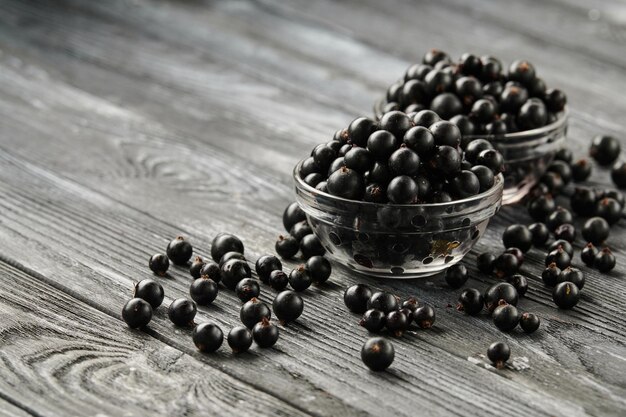 Grosellas negras maduras en tazones sobre una mesa de madera