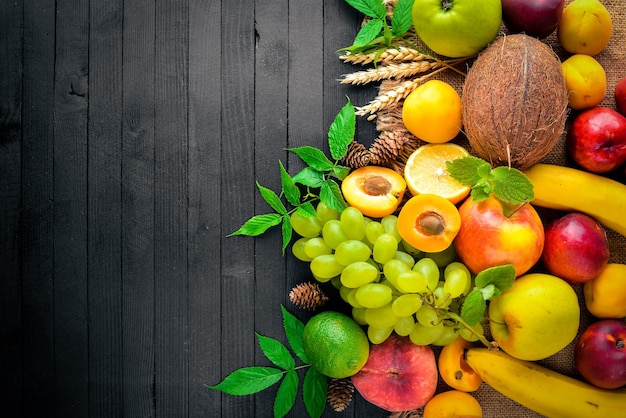 Große auswahl an frischem obst auf einem schwarzen holztisch freier platz für ihren text ansicht von oben