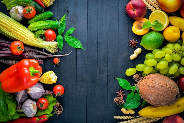Große Auswahl an rohem Gemüse und Obst auf einem schwarzen Holztisch Freier Platz für Ihren Text Ansicht von oben