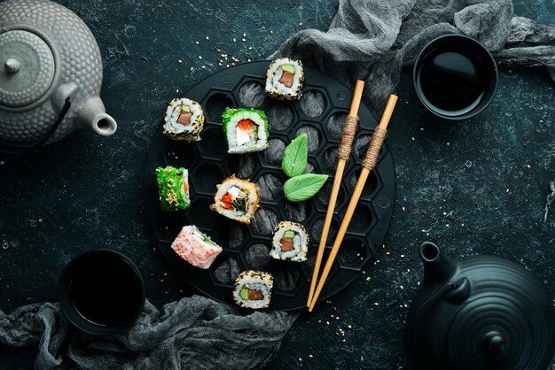 Große Auswahl an Sushi-Rollen mit Meeresfrüchten auf schwarzem Steinhintergrund Draufsicht Freier Platz für Ihren Text