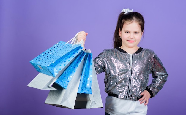 Große Auswahl Mädchen mit Einkaufstüten violettem Hintergrund Einkaufen und Einkaufen Schwarzer Freitag Verkaufsrabatt Einkaufstag Kinder halten Haufenpakete Kindermode Überraschungsgeschenk Tolle Geschäfte