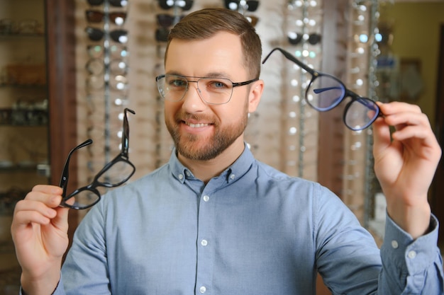 Große Auswahl Stilvoller Mann mit Bart, der im Optikgeschäft eine Brille auswählt