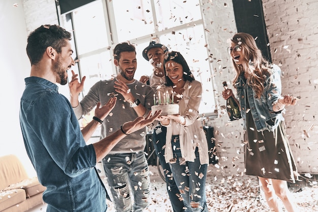 Große Überraschung! Glücklicher junger Mann, der unter Freunden Geburtstag feiert