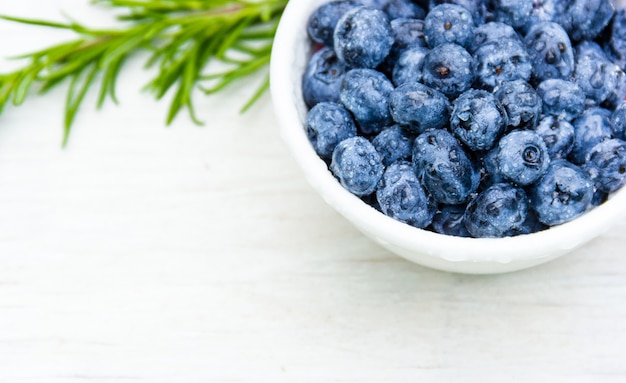 Große Blaubeeren in einer weißen Tasse auf einem weißen Tisch. Speicherplatz kopieren