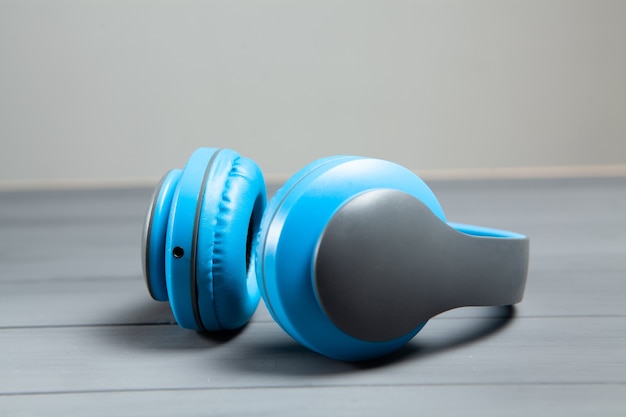 Große blaue Kopfhörer auf grauem Holztisch