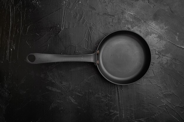 Große Bratpfanne mit Kopienraum für Text oder Essen mit Kopienraum für Text oder Essen, Draufsicht flach, auf schwarzem, dunklem Steintischhintergrund