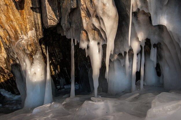 Große dicke Eiszapfen auf den Felsen und mehrere Eisstalagmiten. Eiszapfen sind in der Sonne geschmolzen.