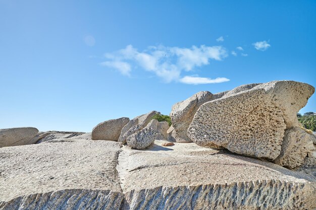 Große Felsbrocken an einer felsigen Küste draußen an einem Sommertag Landschaftsansicht eines schönen Strandes und der Küste unter einem klaren blauen Himmel Eine natürliche Umgebung am Meer und Meereslebensraum mit Kopierraum