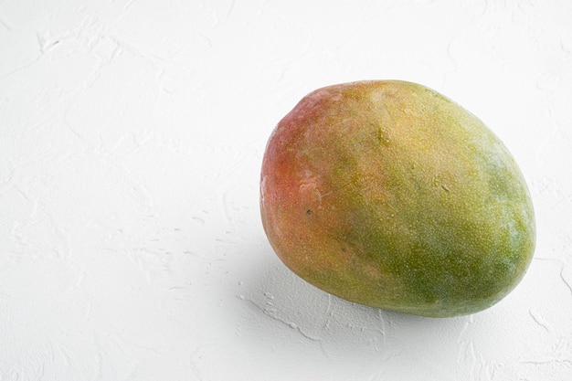 Große ganze leckere Mango auf weißem Steintischhintergrund mit Kopierraum für Text