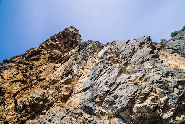 Große Gebirgsklippe unter Nahaufnahme des bewölkten Himmels.