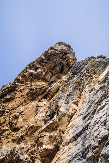 Große Gebirgsklippe unter Nahaufnahme des bewölkten Himmels.